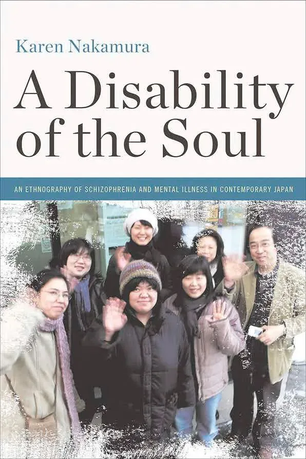 书影,《A Disability of the Soul: An Ethnography of Schizophrenia and Mental Illness in Contemporary Japan》书封,作者Karen Nakamura,下方是一张多人户外合影,几位社区成员微笑并挥手。