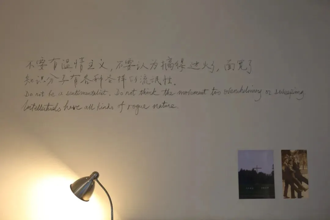 墙上手写着中英文对照的引文：「不能有温情主义，不要认为搞得过火了、面宽了。知识分子有各种各样的流氓性。」墙角亮着一盏台灯，右下角贴着两张小照片。