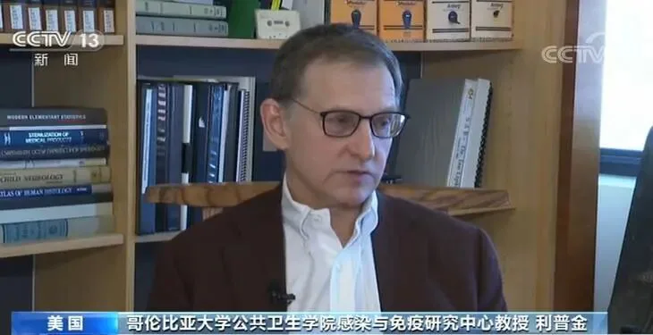 央视新闻画面，字幕显示“美国 哥伦比亚大学公共卫生学院感染与免疫研究中心教授 利普金”，一位戴眼镜、穿栗色外套的男性正接受采访，身后是书架。